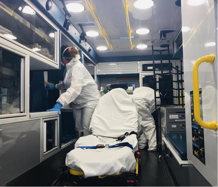 SERVPVRO Techs, dressed in PPE, clean the inside of an ambulance