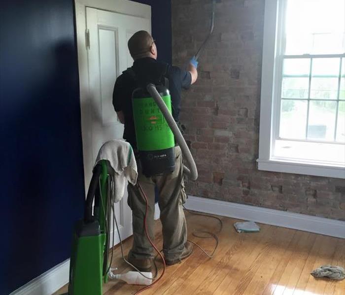 male employee using green SERVPRO equipment to clean a brick wall