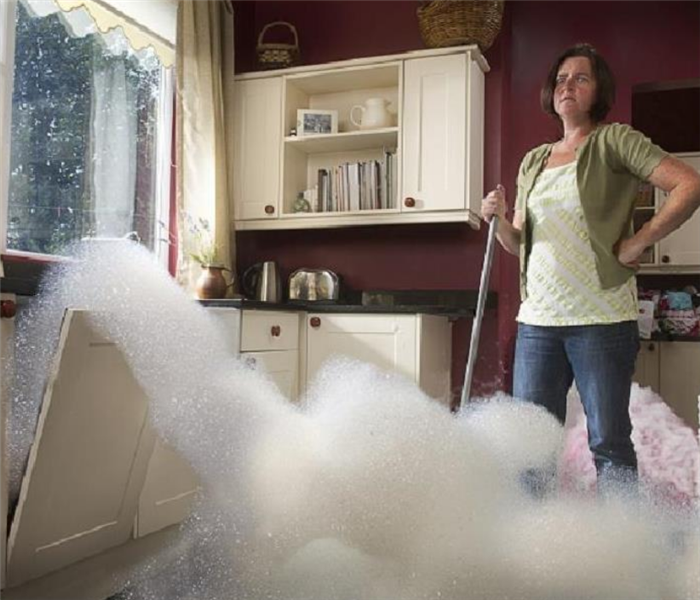 a woman in her kitchen staring at the bubbles coming out of her dishwasher