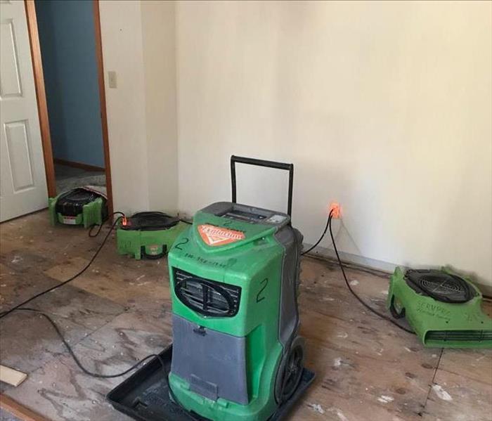 A room with wood subflooring, with SERVPRO equipment on the floor. 
