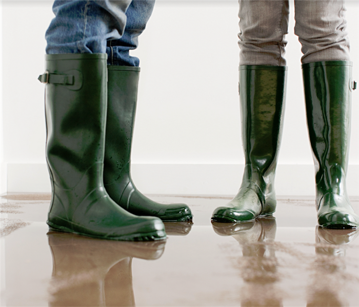 two people standing in rain boots in a flooded room
